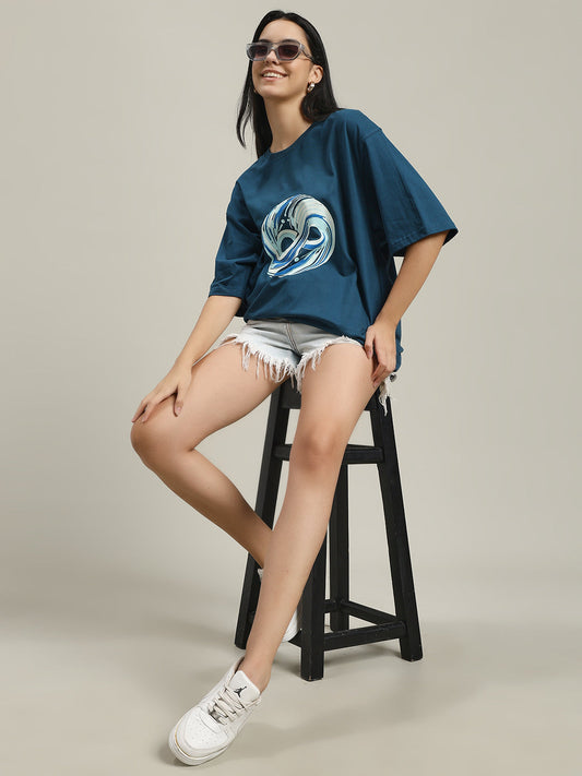 Woman smiling wearing a blue women’s over-sized tee with a circular abstract design, standing against a plain beige background The Quietest Cult You’ll Ever Join-women's over-sized tee