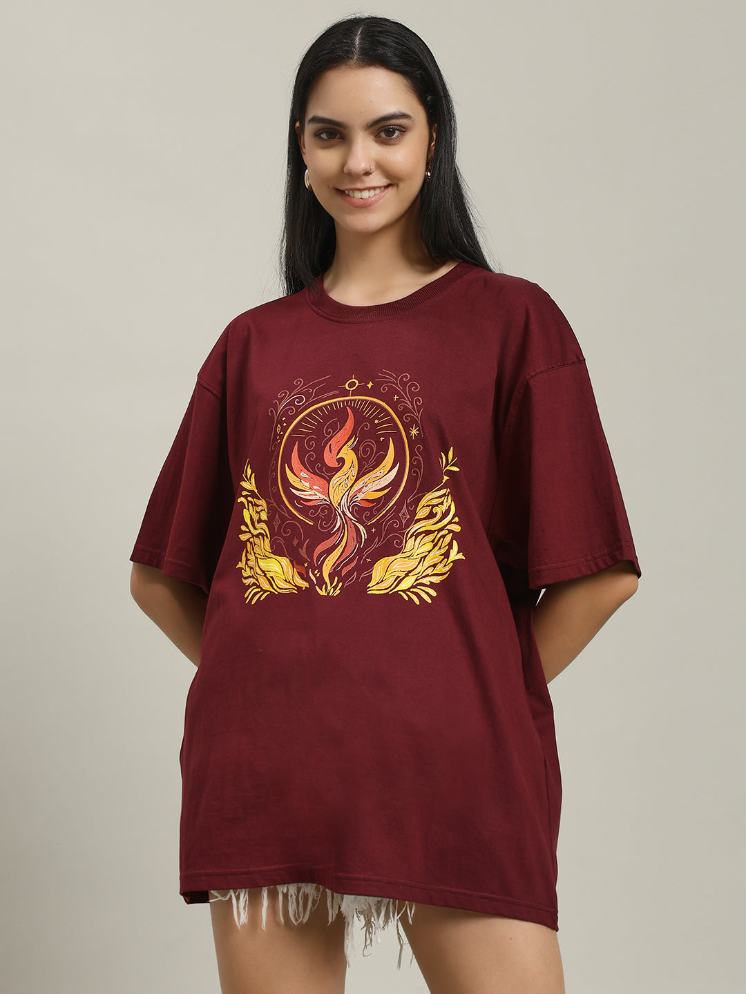 Close-up of a woman wearing a maroon Fire women's over-sized T-shirt with a detailed phoenix and fire graphic on the front, showing the design and fabric texture